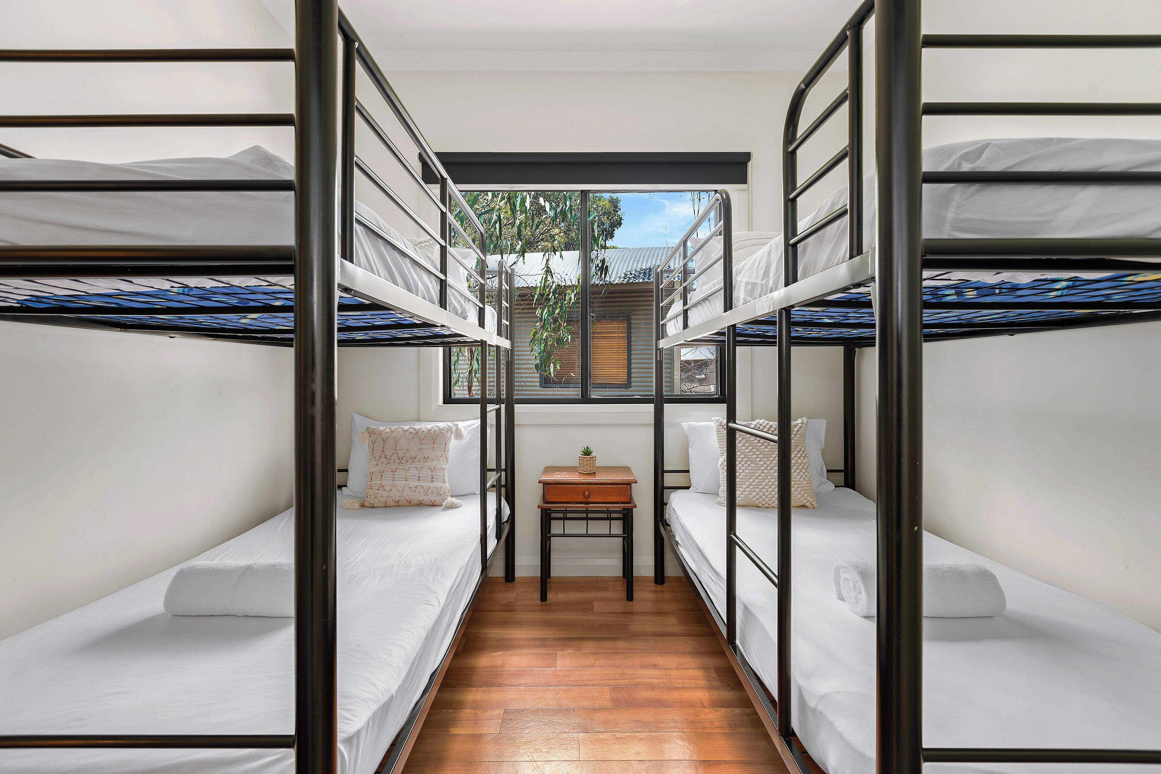 A bunk bed room with a small table and a window.