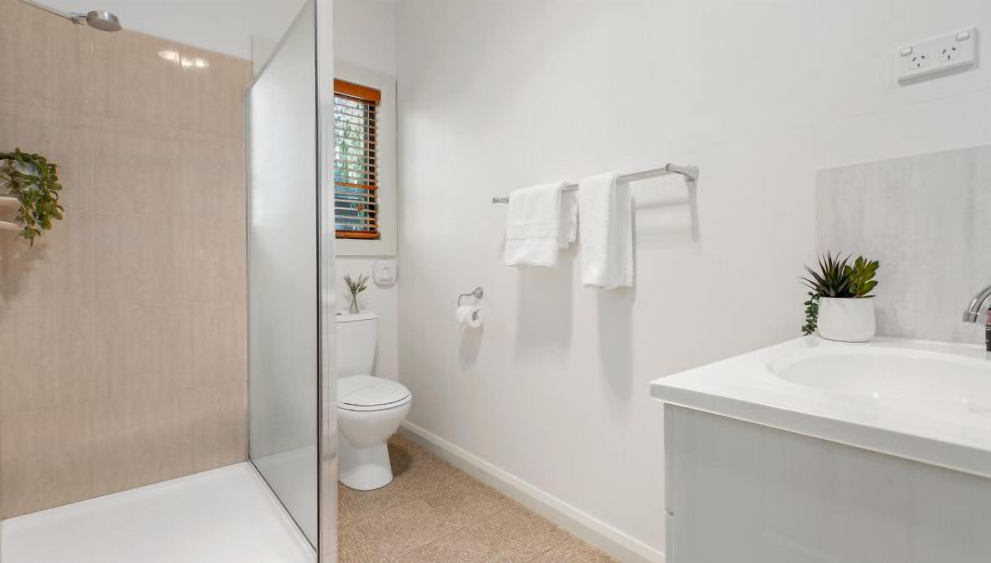 A modern bathroom with a shower, toilet, and sink.