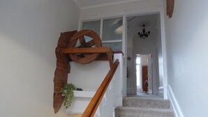 Una escalera con barandilla de madera, un adorno en la pared y una planta en maceta.