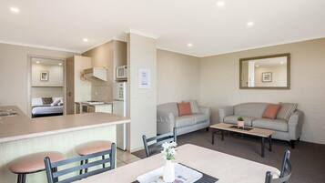A compact living space with a kitchenette, a dining area, and a seating area with a sofa and a coffee table.