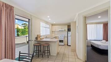 A compact hotel room with a kitchenette, a dining area with stools, and a bed.