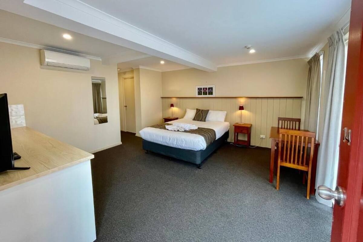 A hotel room with a bed, bedside tables, a desk, and a chair.