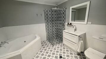 A bathroom with a bathtub, a shower, a sink, and a toilet.