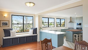 A modern kitchen with a central island, built-in appliances, and large windows offering a view of the outdoors. - Heritage House Motel & Units (Eden)