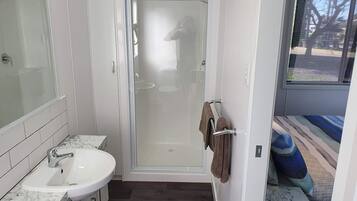 A modern bathroom with a glass-enclosed shower, a white sink with a marble countertop, and a towel rack with a brown towel.