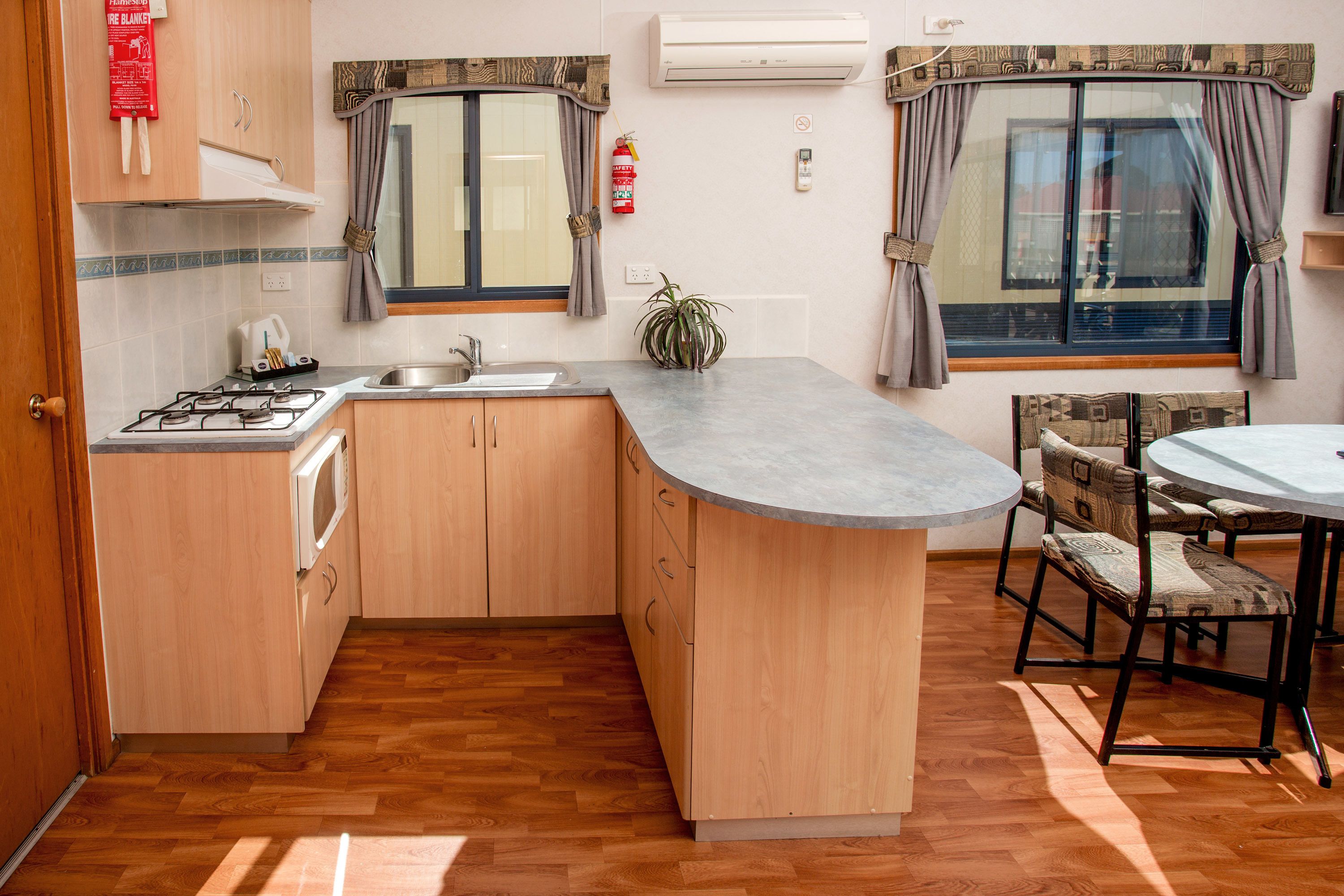 Una cocina compacta con armarios de madera, estufa a gas, lavamanos y comedor con mesa y sillas.