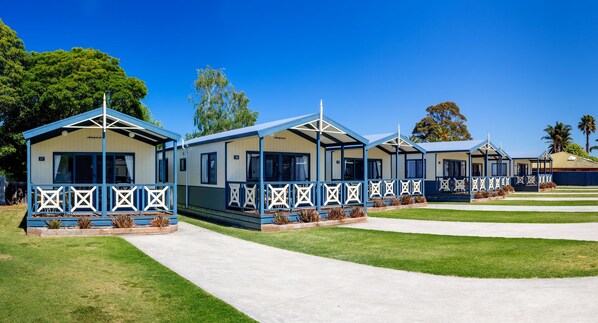 A row of blue and white mobile homes with a uniform design, each featuring a porch with decorative railings. - BIG4 Whiters Holiday Village (Lakes Entrance)