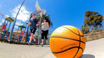 A basketball on a concrete surface with a clear blue sky in the background.