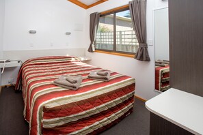 A hotel room with a bed, a desk, and a window. - BIG4 Whiters Holiday Village (Lakes Entrance)