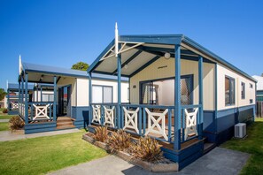A mobile home with a covered porch, a fenced yard, and a well-maintained lawn. - BIG4 Whiters Holiday Village (Lakes Entrance)