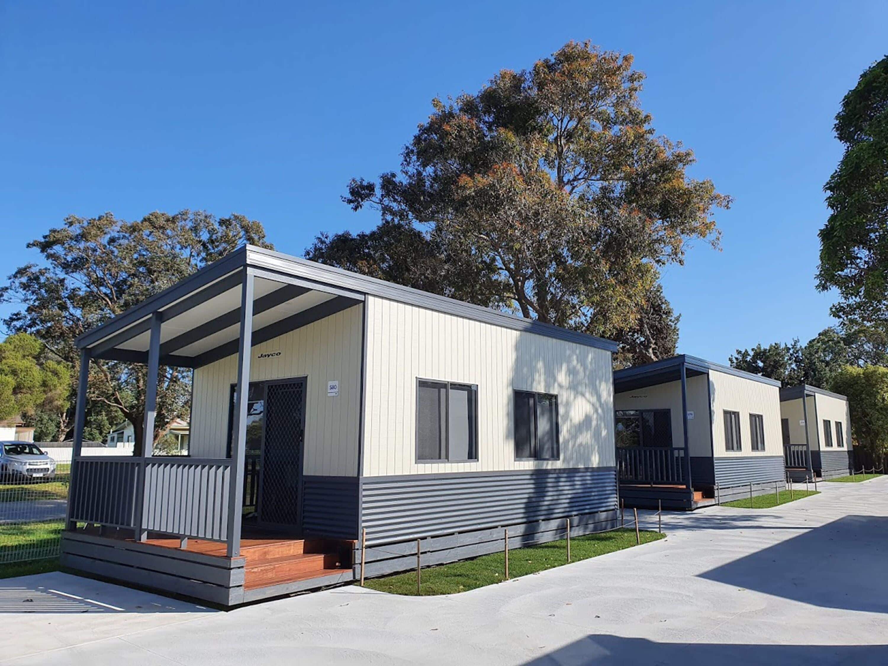 A modern mobile home with a covered porch, a small front deck, and a garage.