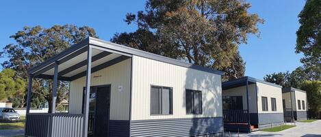 A modern mobile home with a covered porch, a small front deck, and a garage.
