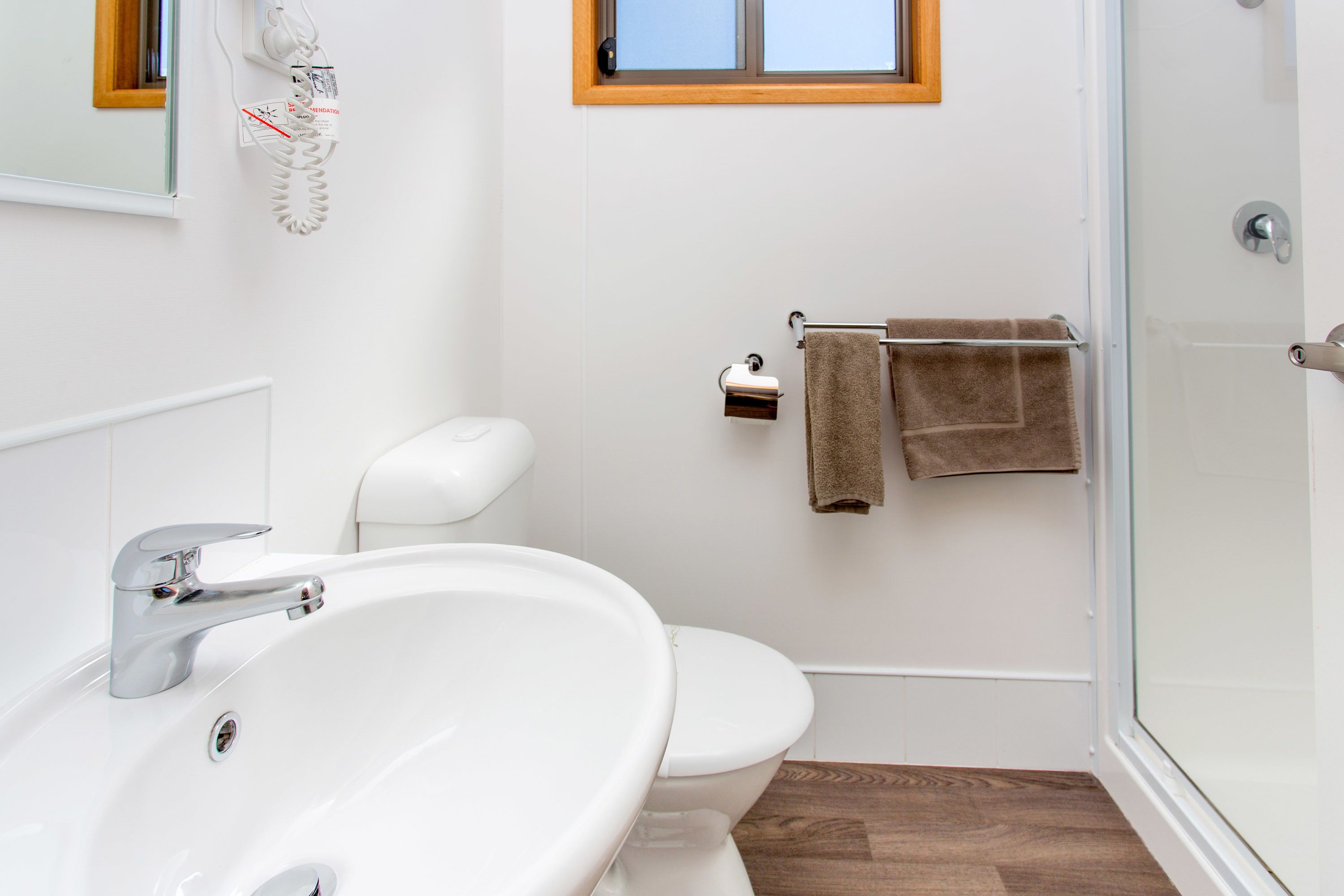 A modern bathroom with a white sink, toilet, and glass shower enclosure.