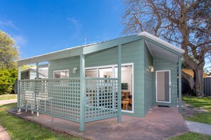 Un petit bâtiment d’un seul étage, doté d’un porche et d’un espace clos, probablement une maison de campagne ou une dépendance.