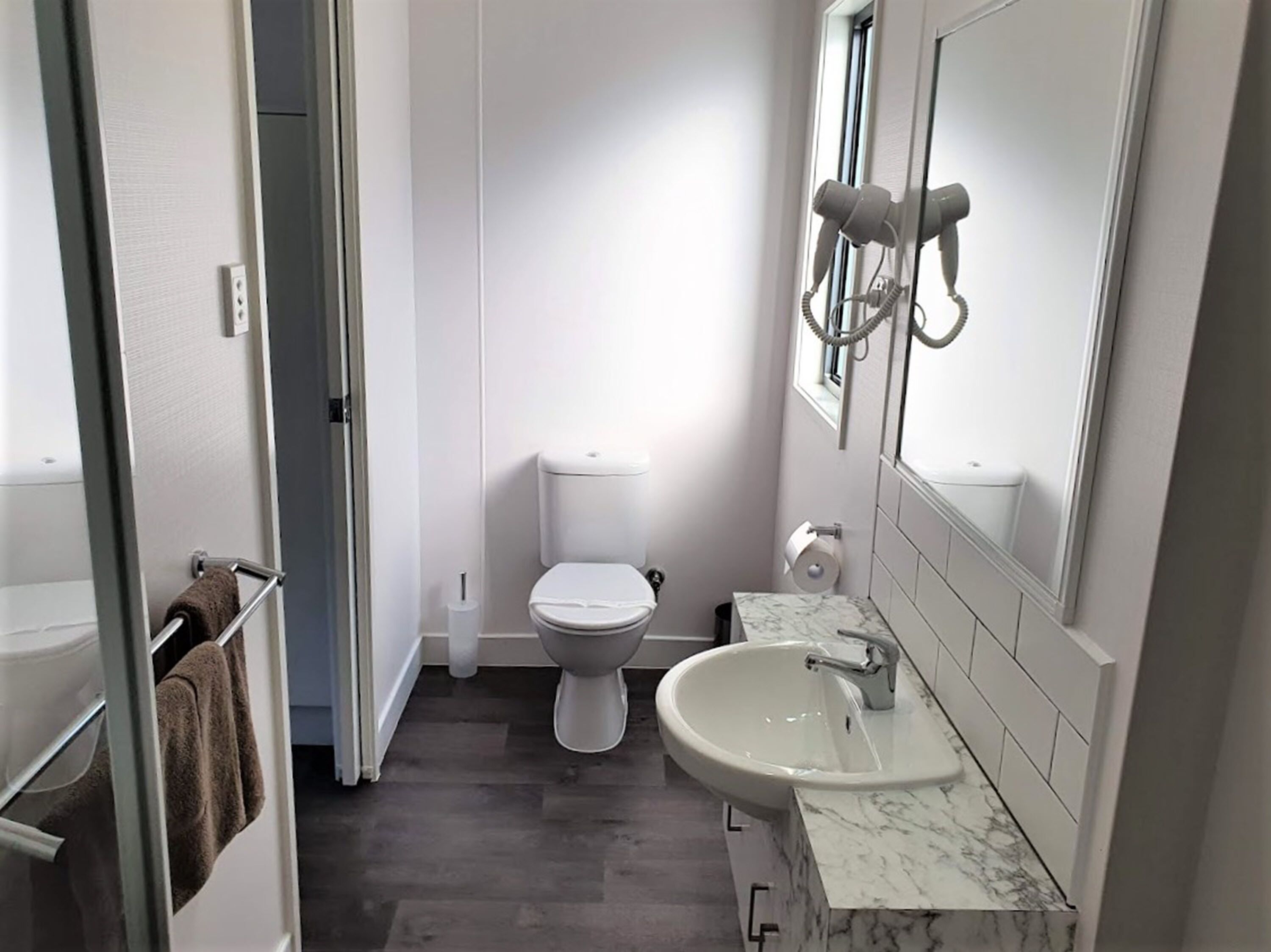 Een kleine badkamer met toilet, wastafel en handdoekhouder.