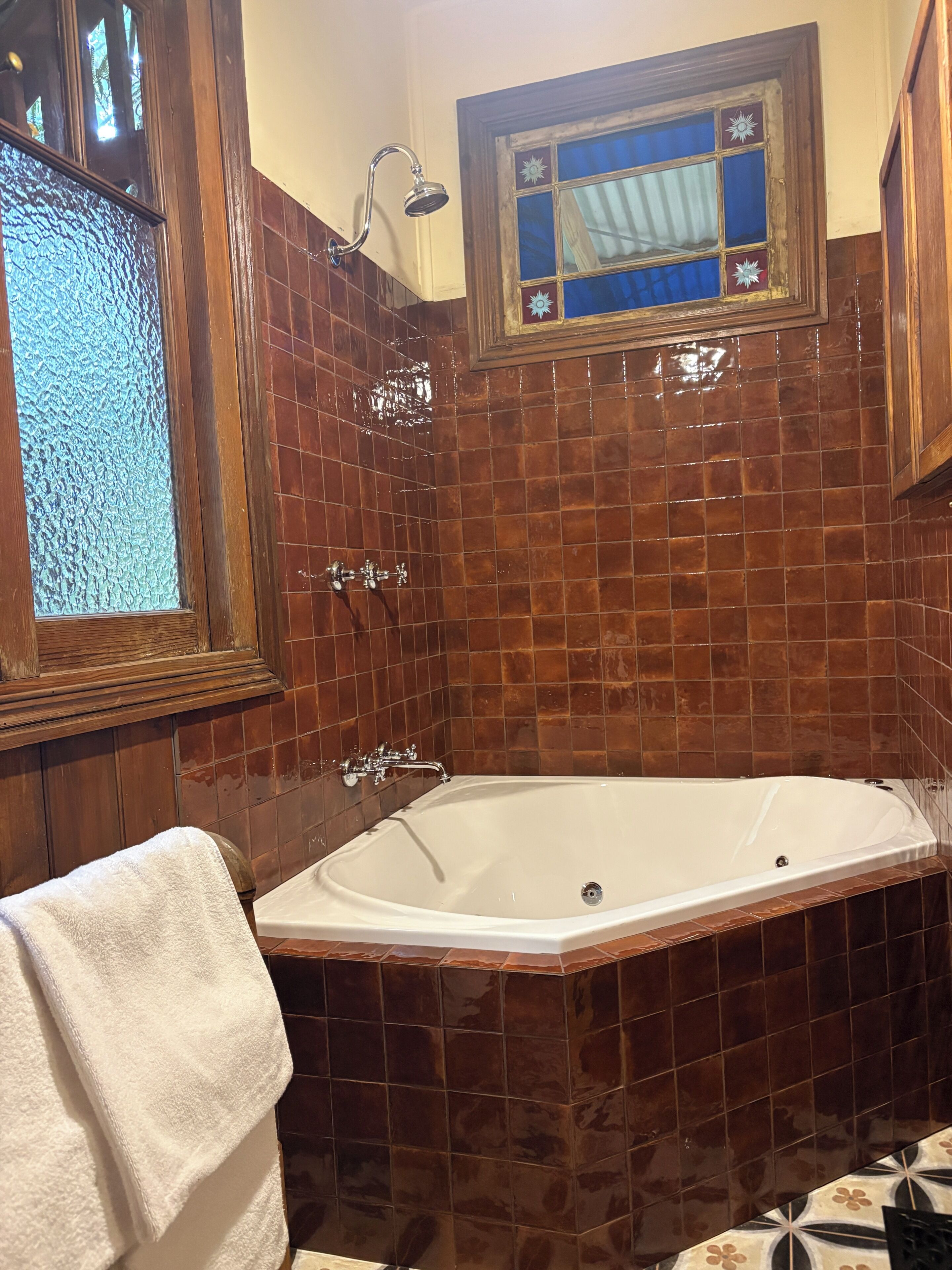 Un baño con bañera, ducha y ventana con un marco decorativo.