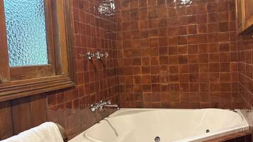Une salle de bain équipée d’une baignoire, d’une douche et d’une fenêtre agrémentée d’un cadre décoratif.