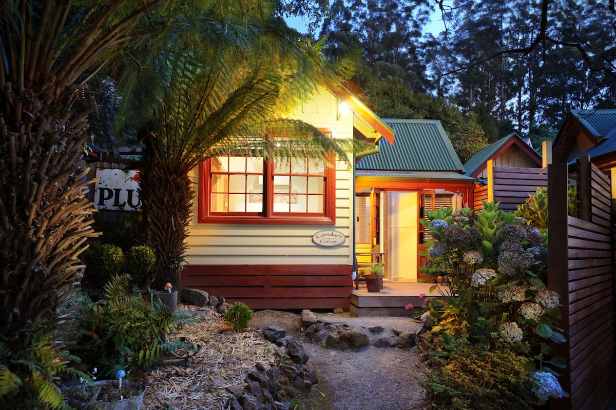 A cozy cabin with a wooden exterior, a porch, and a sign that reads "Caretaker's Cottage."