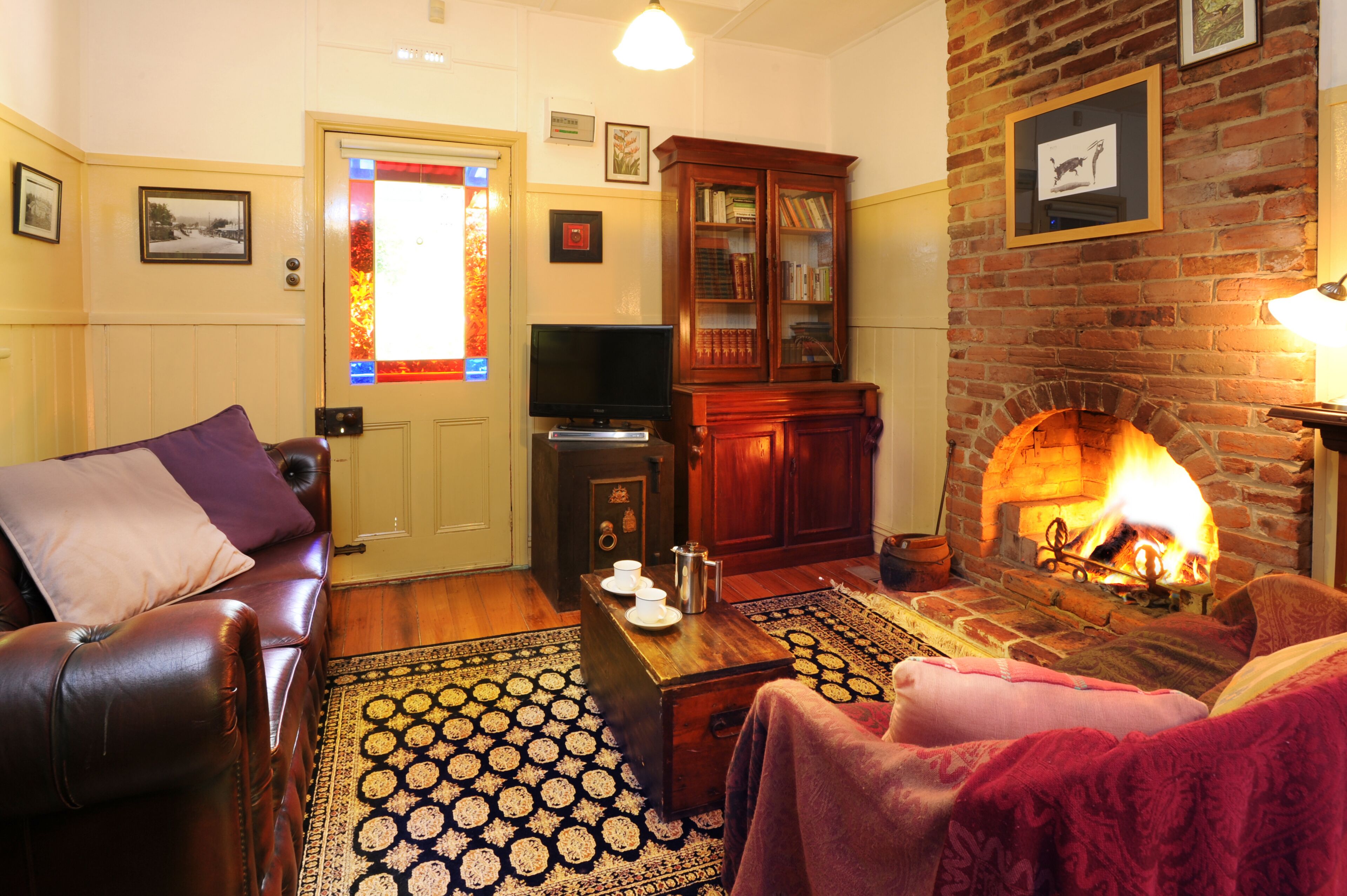 A cozy living room with a fireplace, leather sofa, and a television.