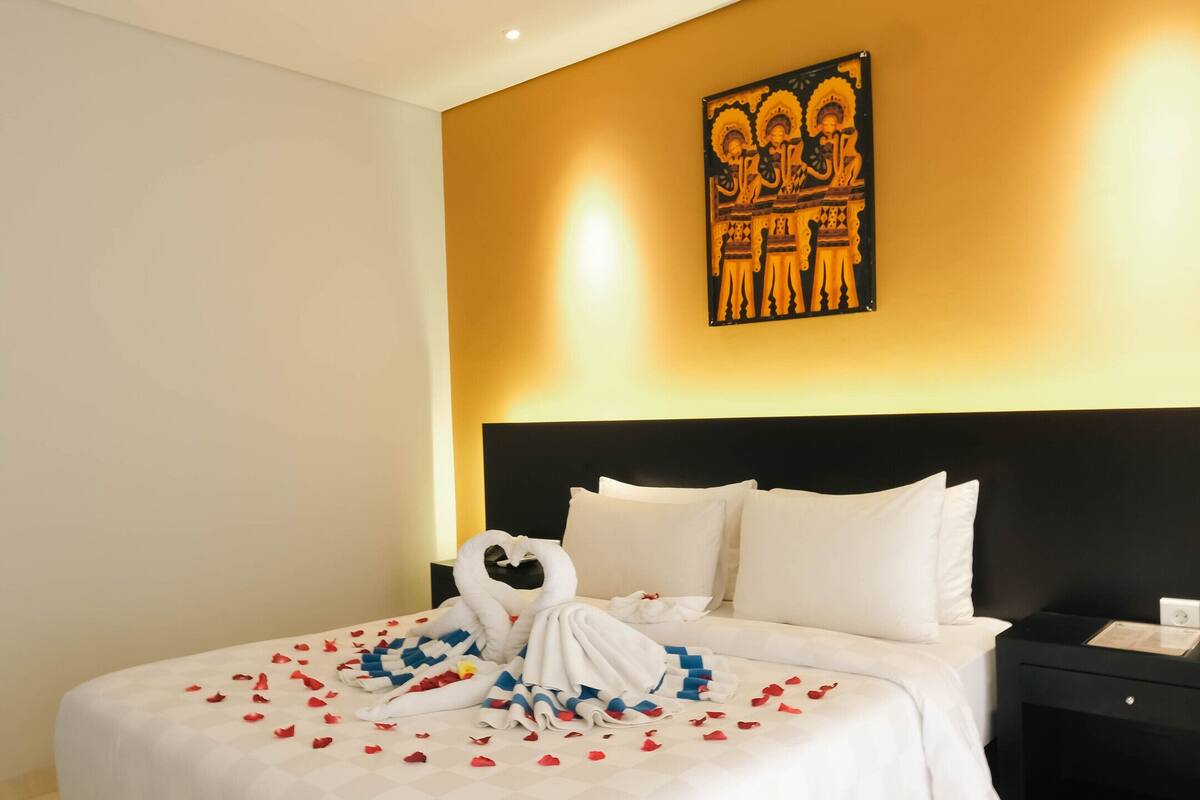 A hotel room with a large bed, a nightstand, and a wall-mounted artwork.