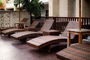 Un área de sol con sillones de mimbre y una mesita.