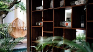 A wooden shelf with glass bottles and a woven basket. - Fourteen Roses Beach Hotel (Legian)