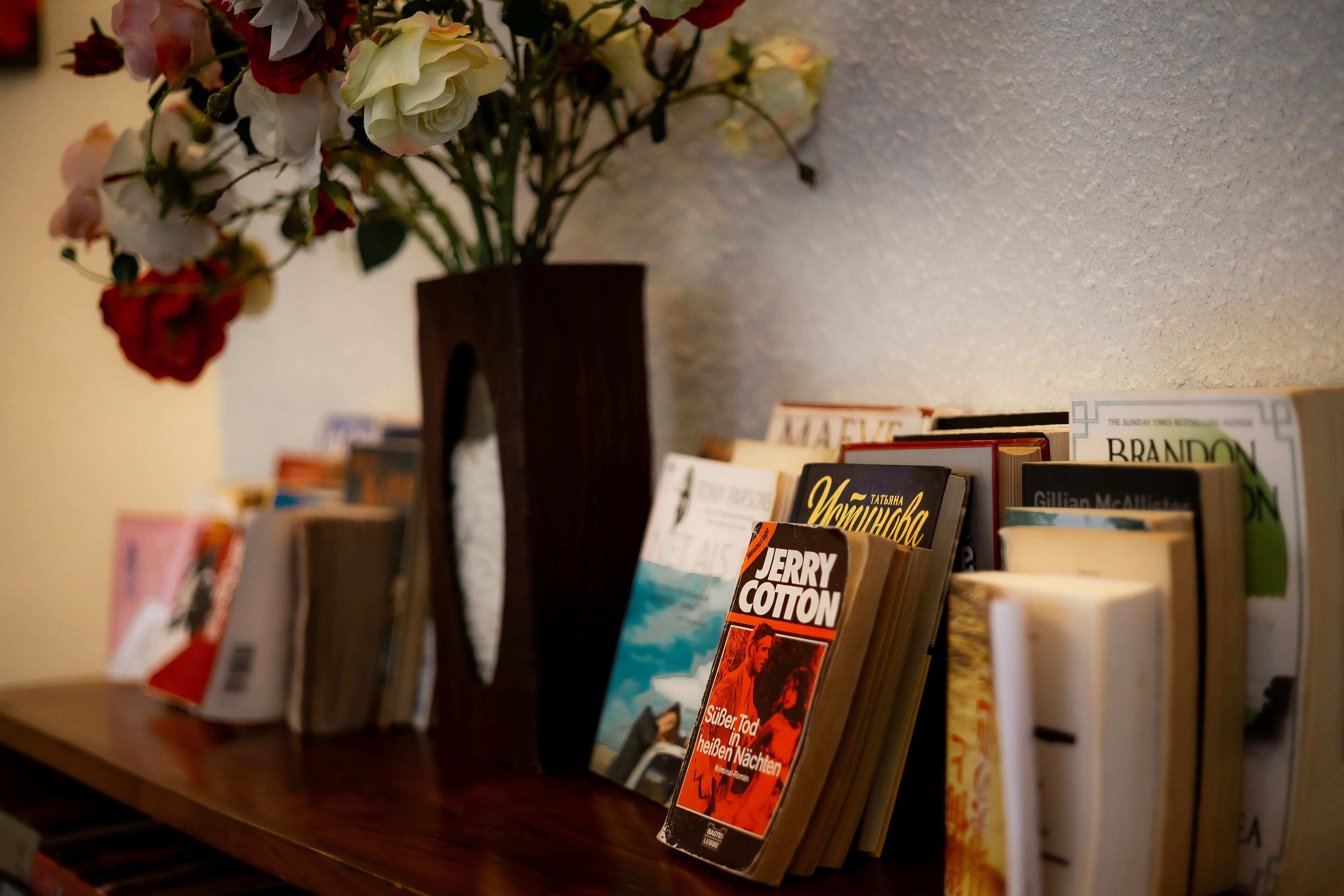 A bookshelf with books and a vase of flowers.