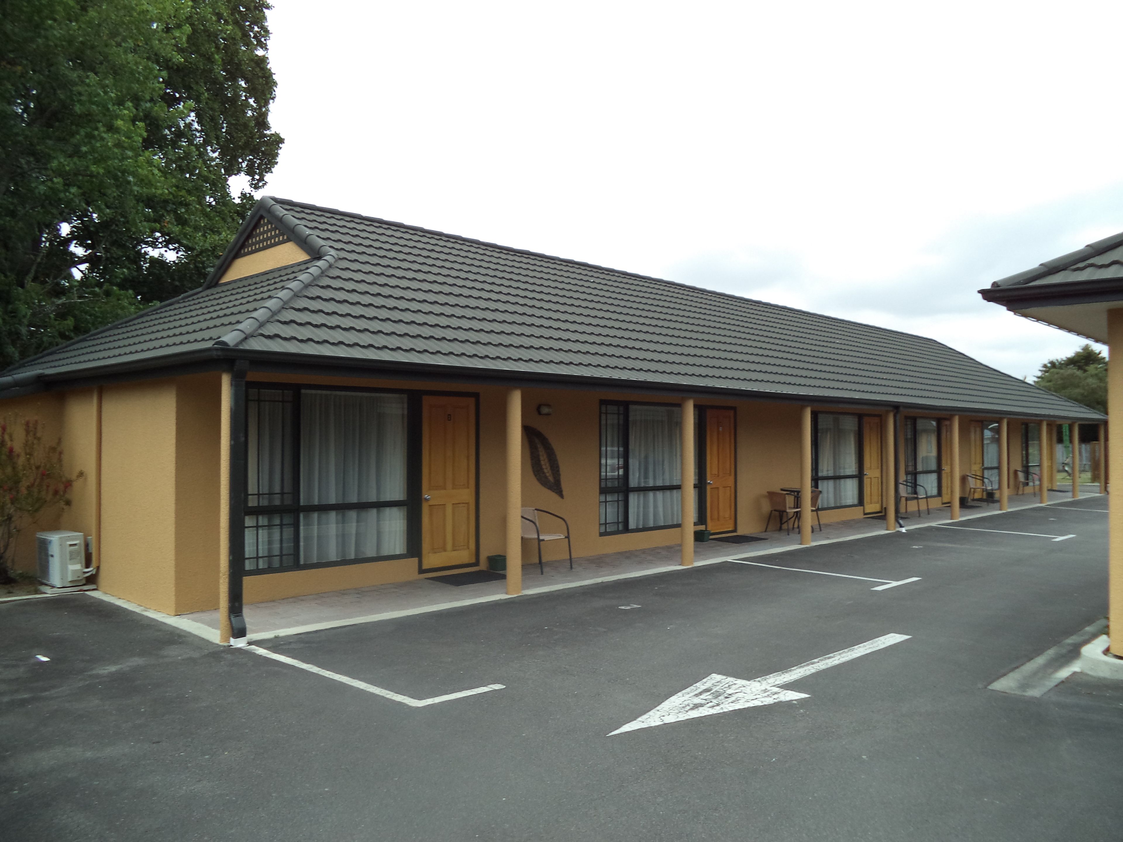 A motel with a single-story structure, a tiled roof, and a parking lot with directional arrows.