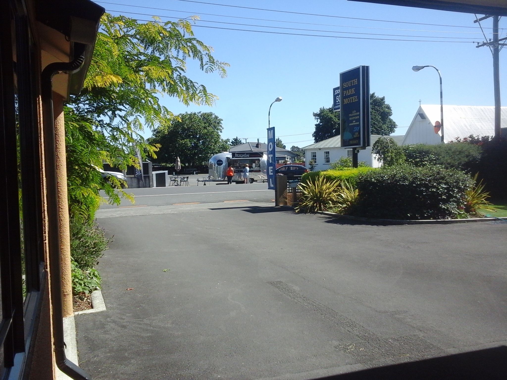 Um motel com uma placa, área de estacionamento e um edifício ao fundo.