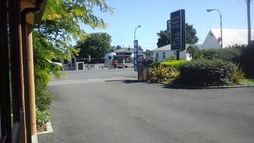 Um motel com uma placa, área de estacionamento e um edifício ao fundo.