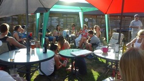 A group of people seated at round tables under umbrellas in an outdoor setting. - South Park Motel (Masterton)