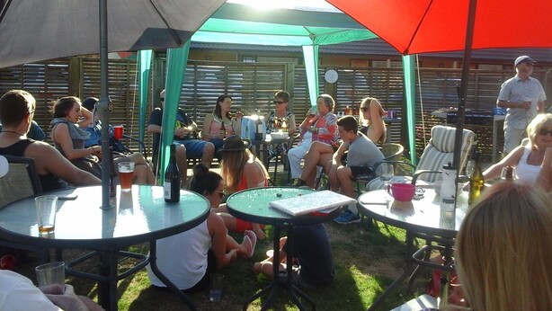 A group of people seated at round tables under umbrellas in an outdoor setting. - South Park Motel (Masterton)