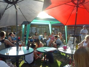 A group of people seated at round tables under umbrellas in an outdoor setting. - South Park Motel (Masterton)