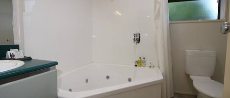 Et badeværelse med badekar, toilet og håndvask.