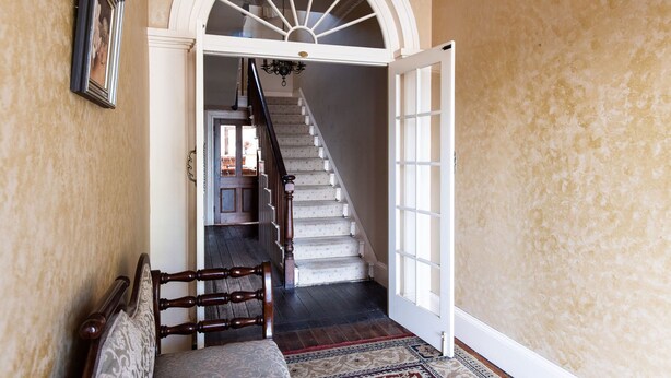 A staircase with a white door at the top, a wooden chair, and a patterned rug. - Fitzpatrick's Inn (Westbury)
