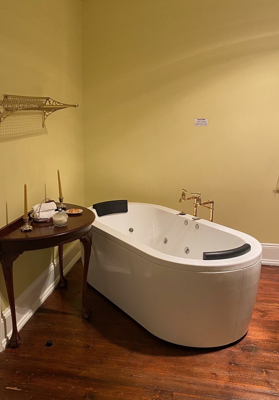 Un baño con una bañera independiente, una mesita con velas y un aplique de pared.