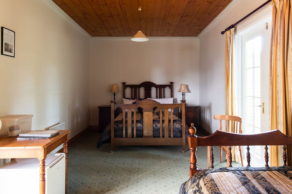 Un dormitorio con techo de madera, una cama con cabecera, una mesita de noche, un escritorio y una silla.