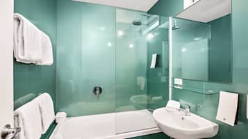 A modern bathroom with a glass-enclosed shower, a white sink, and a glass shelf.