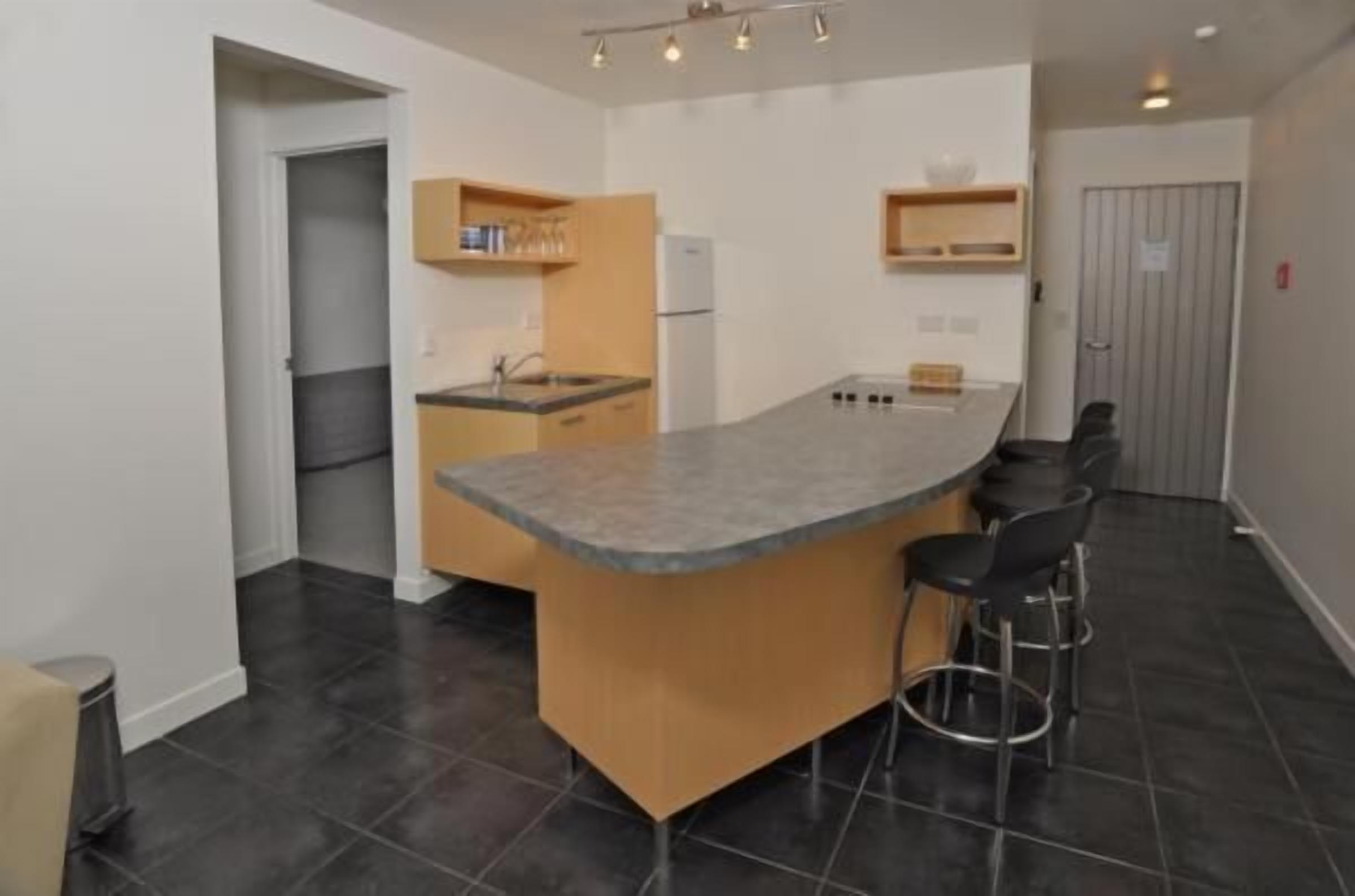 A compact kitchen with a central island, bar stools, and built-in appliances.