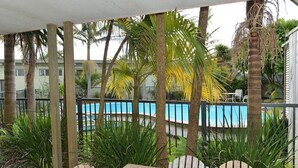 A covered outdoor area with a pool, wooden deck, and seating. - Waipu Cove Resort (Waipu)