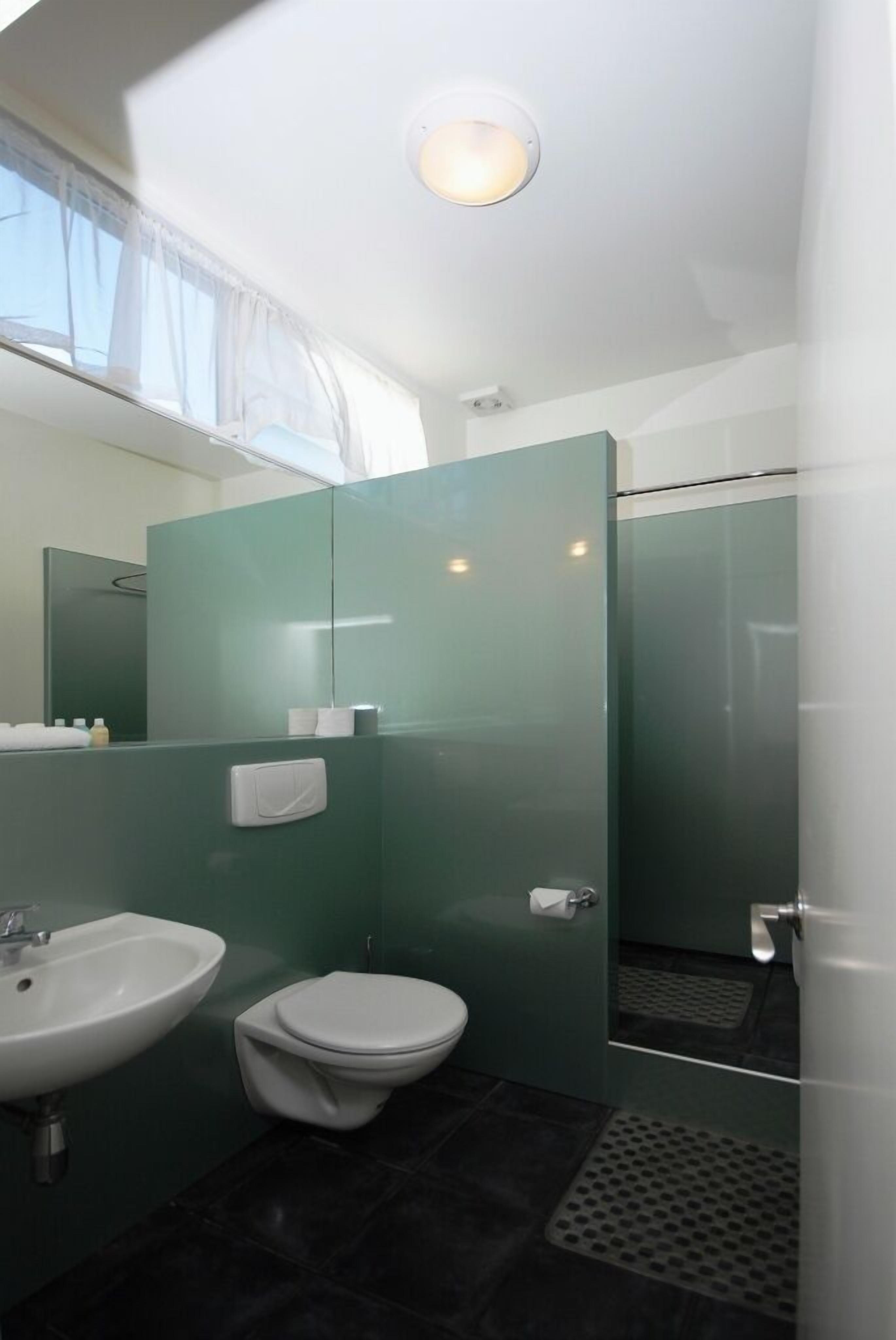 A modern bathroom with a glass shower enclosure, a white sink, and a toilet.
