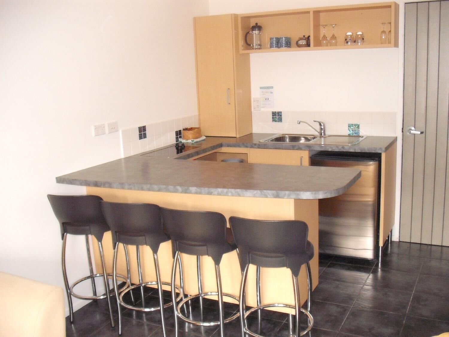 A compact kitchen with a central island, bar stools, and a built-in oven.