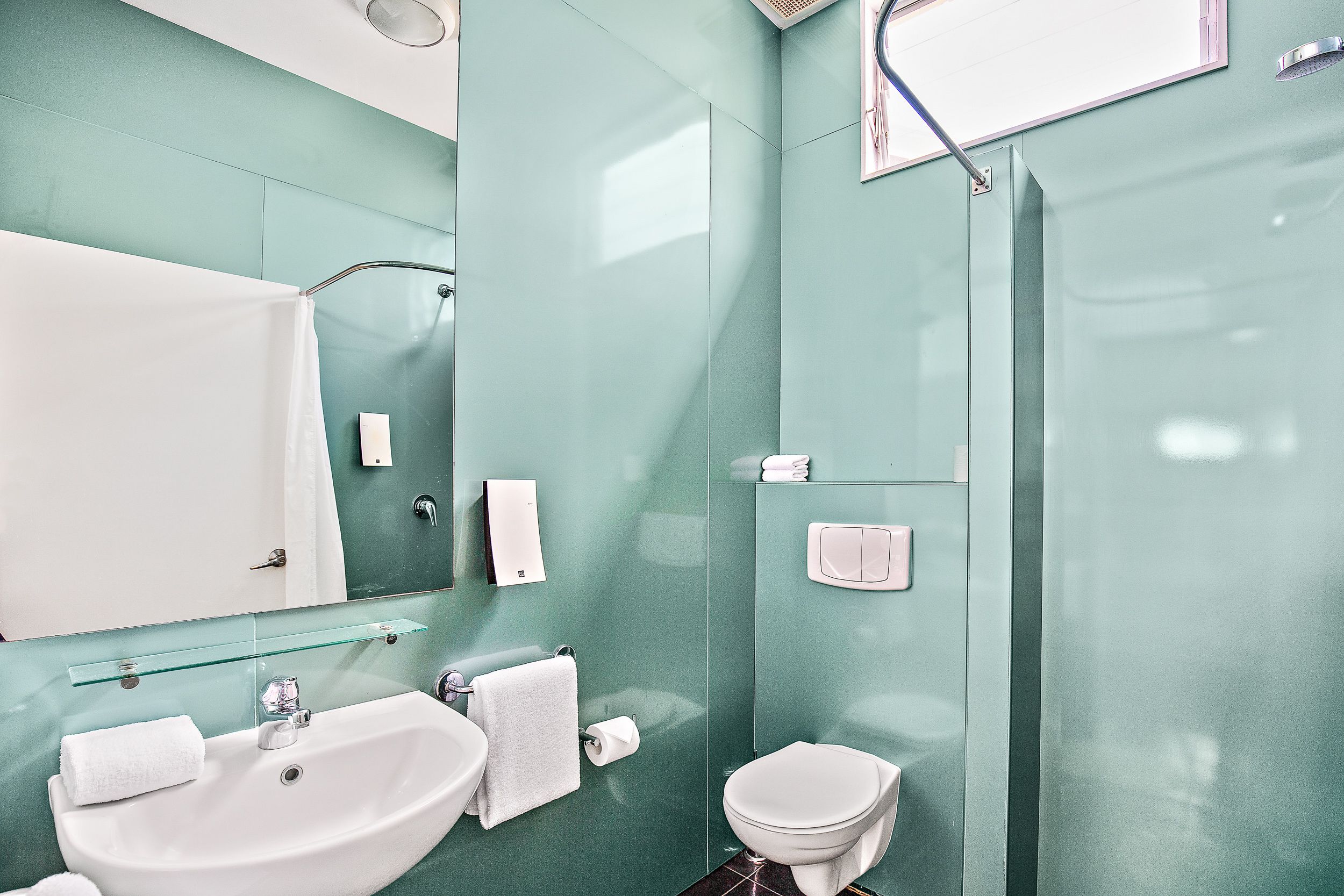 A modern bathroom with a sink, mirror, and toilet.