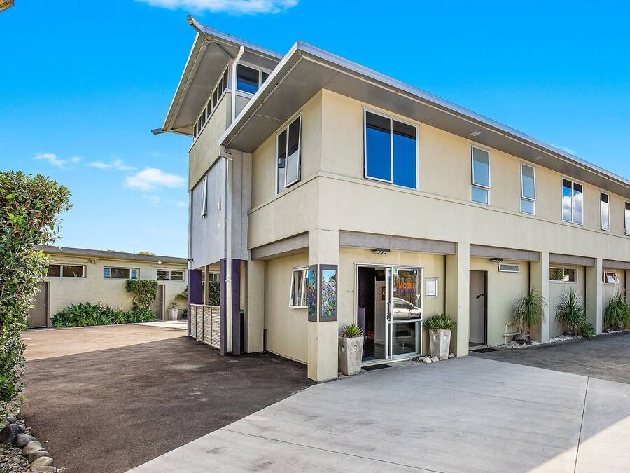A two-story motel with a flat roof and a large entrance door.