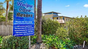 A sign for Waipu Cove Resort with amenities like self-contained apartments, heated swimming pool, and free guest laundry. - Waipu Cove Resort (Waipu)