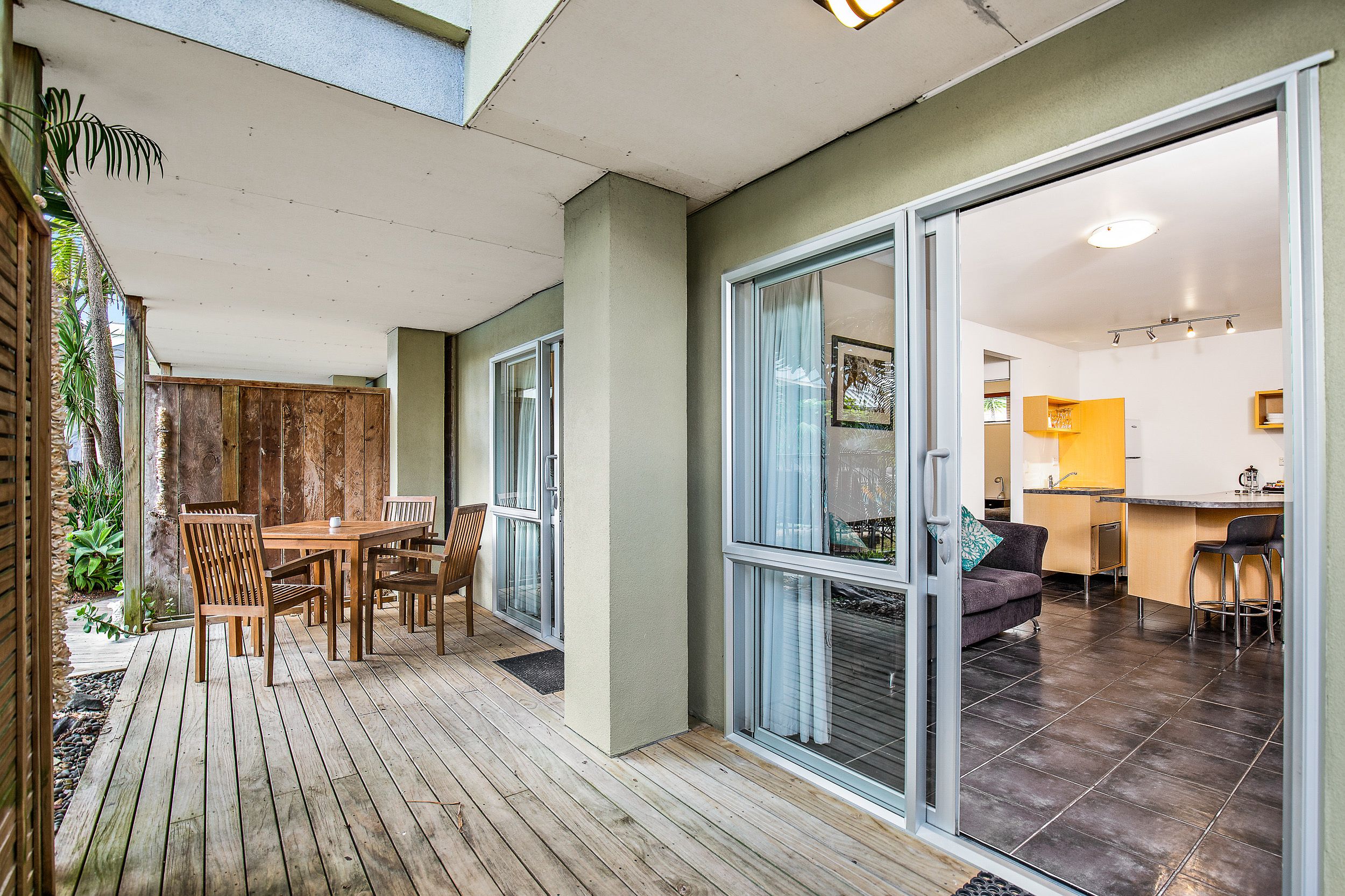 A modern kitchen with a bar area, a dining area with wooden furniture, and a sliding glass door leading to a patio.