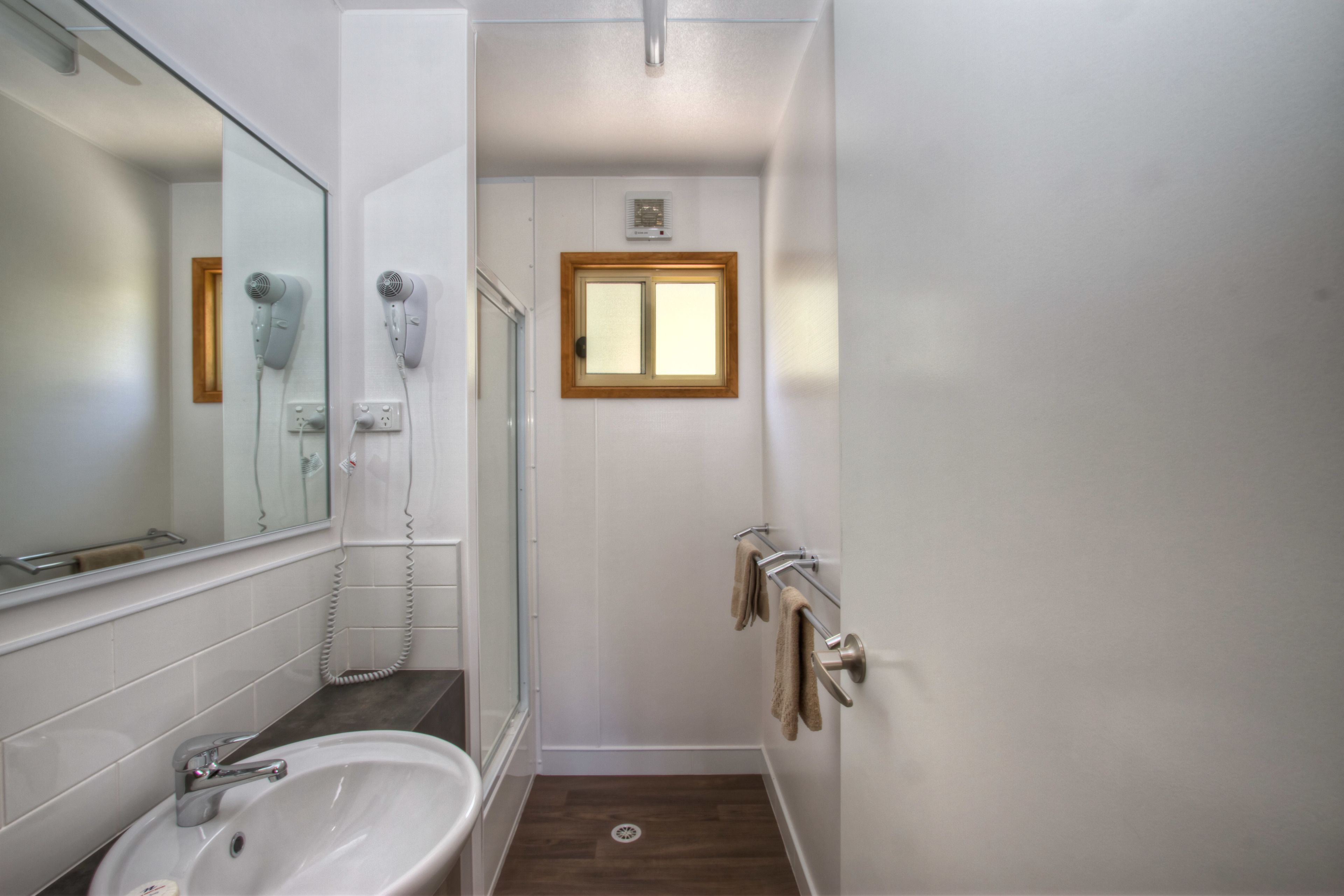 A bathroom with a sink, mirror, hairdryer, and towel rack.