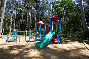 A playground with a slide and climbing structures, surrounded by trees. - Twin Dolphins Holiday Park (Tuncurry)