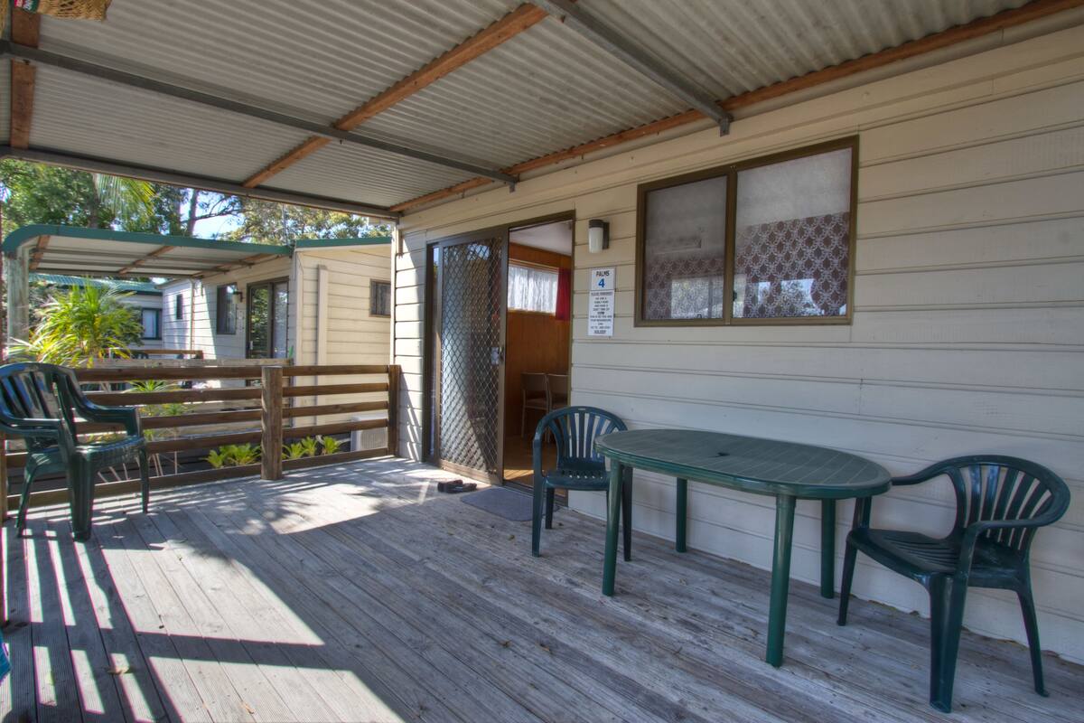A covered outdoor area with a wooden deck, a table with chairs, and a sign indicating room number 4.
