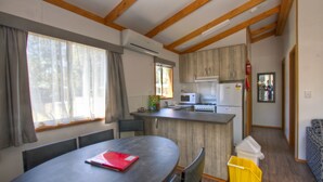 A compact kitchen with a microwave, refrigerator, and wooden cabinets. - Twin Dolphins Holiday Park (Tuncurry)